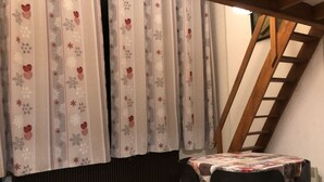 A dining area with a table and chairs, a window with curtains, and a wooden ladder.