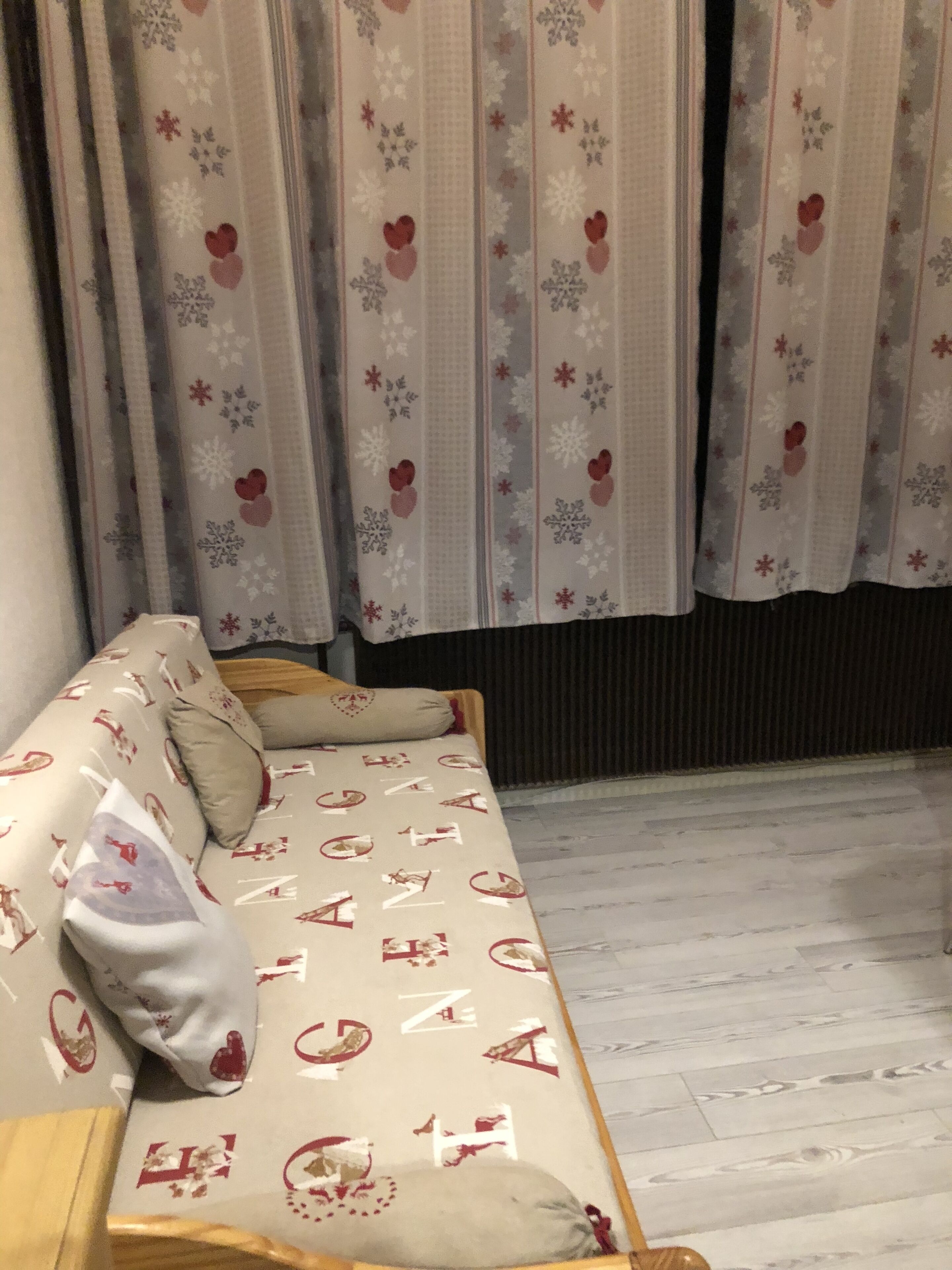 Ein Sofa mit gemustertem Bezug, ein Holztisch und Vorhänge mit Blumenmuster.
