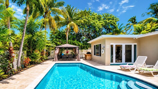 A swimming pool with a gazebo, lounge chairs, and a covered patio area.