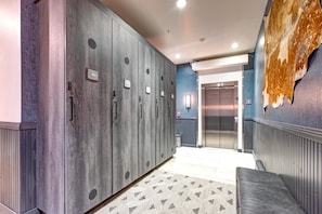 A hallway with lockers, a patterned rug, and an elevator.