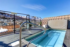 A rooftop pool with a "NO CLIMBING" sign, surrounded by a wooden deck and a metal railing.