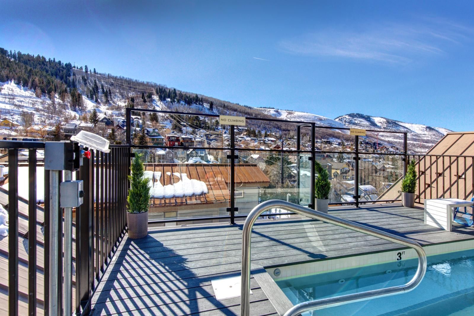 Un espace piscine offrant une vue sur une montagne enneigée et une ville.