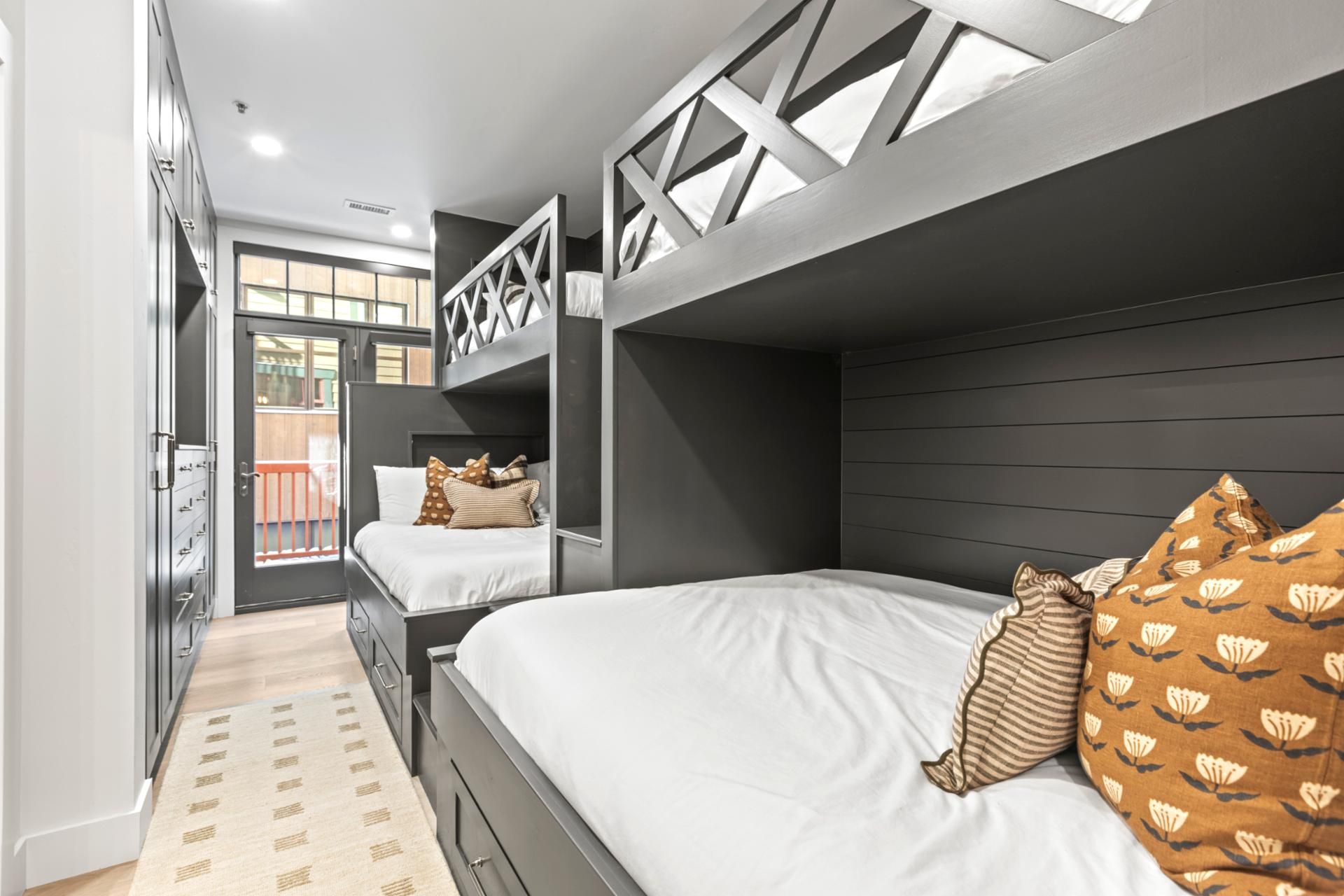 Une chambre d’hôtel moderne avec des lits superposés, un petit balcon et une vue sur l’extérieur.
