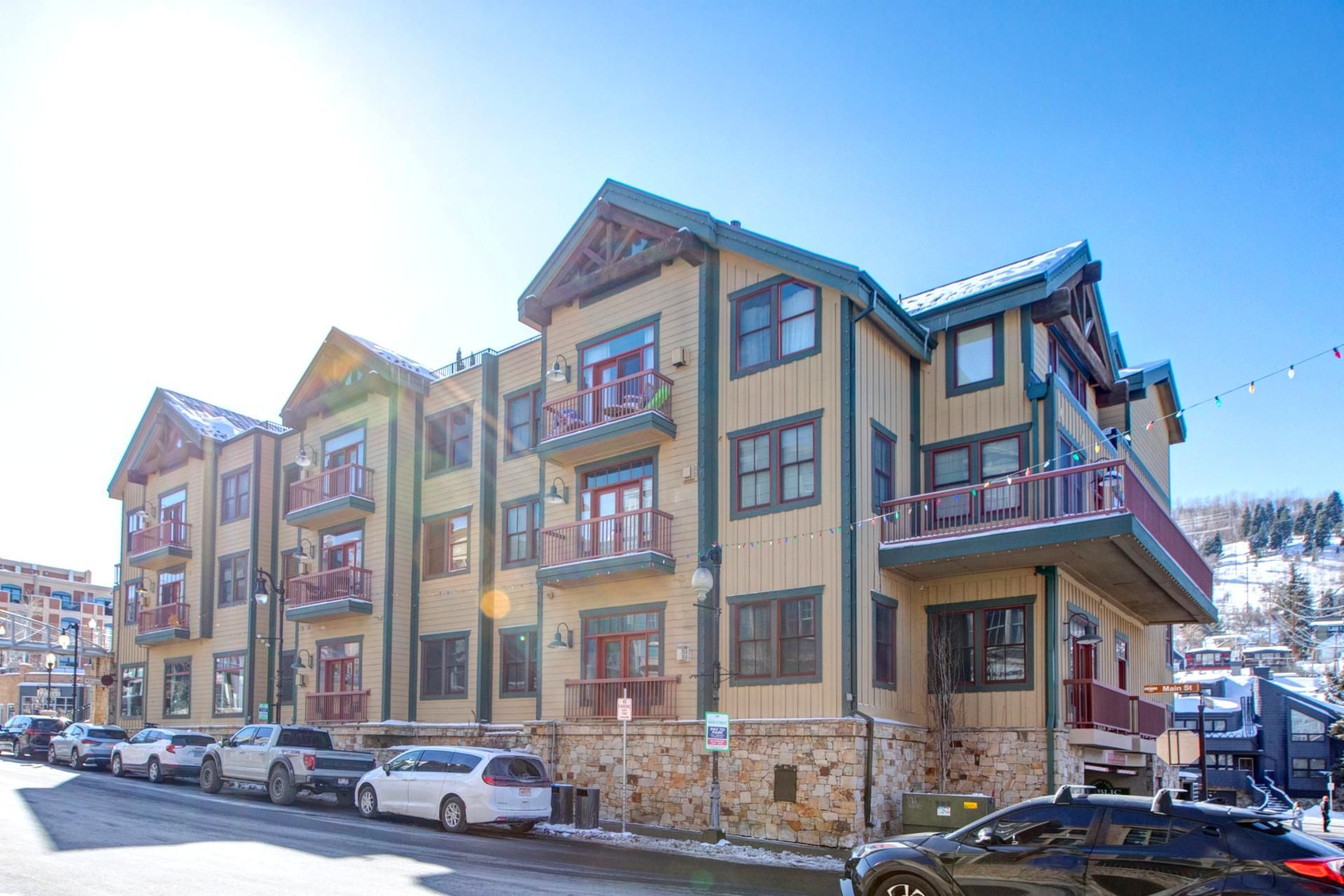 A multi-story hotel with balconies, a parking lot, and a stone facade.