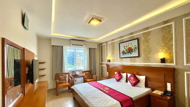 Una habitación de hotel con una cama grande, muebles de madera, un escritorio y una ventana con cortinas.