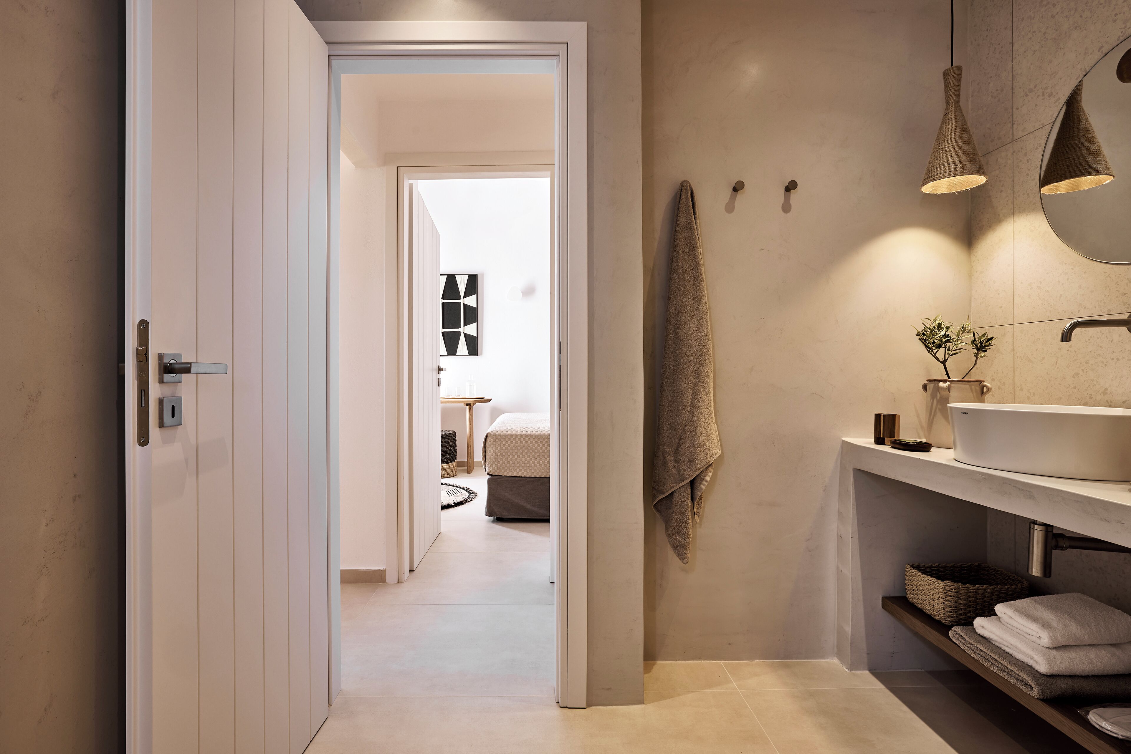 A modern bathroom with a large sink, towel rack, and pendant lights.