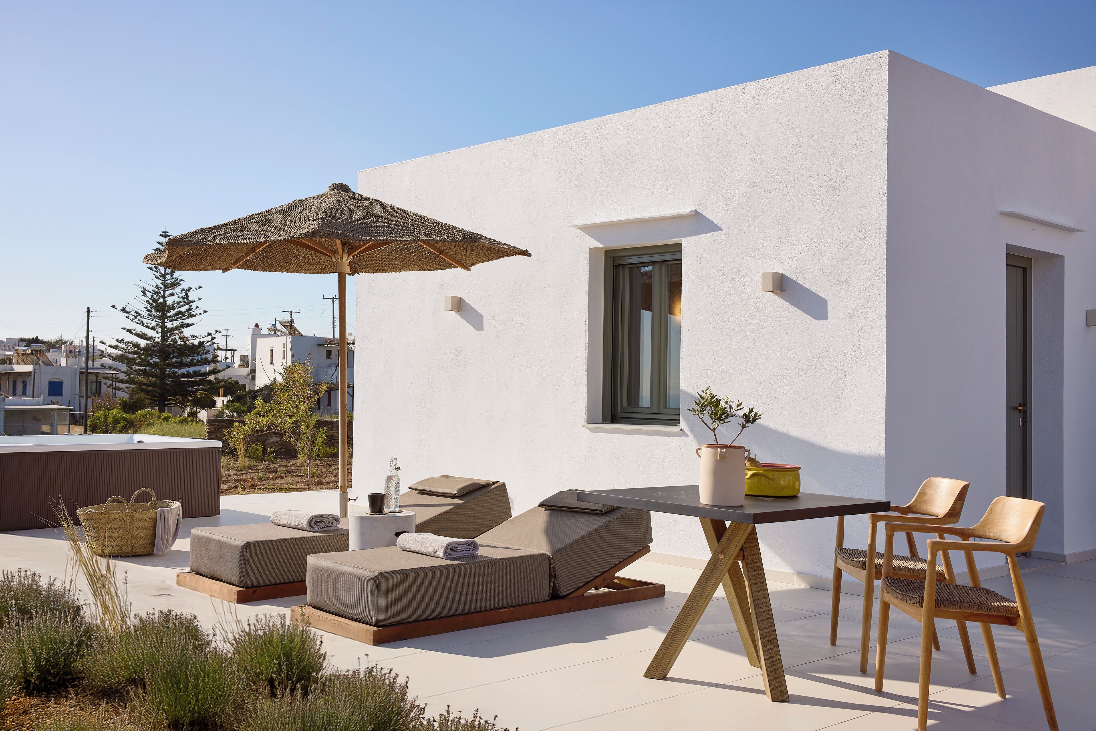 A modern outdoor lounge area with a table, chairs, and a large umbrella.