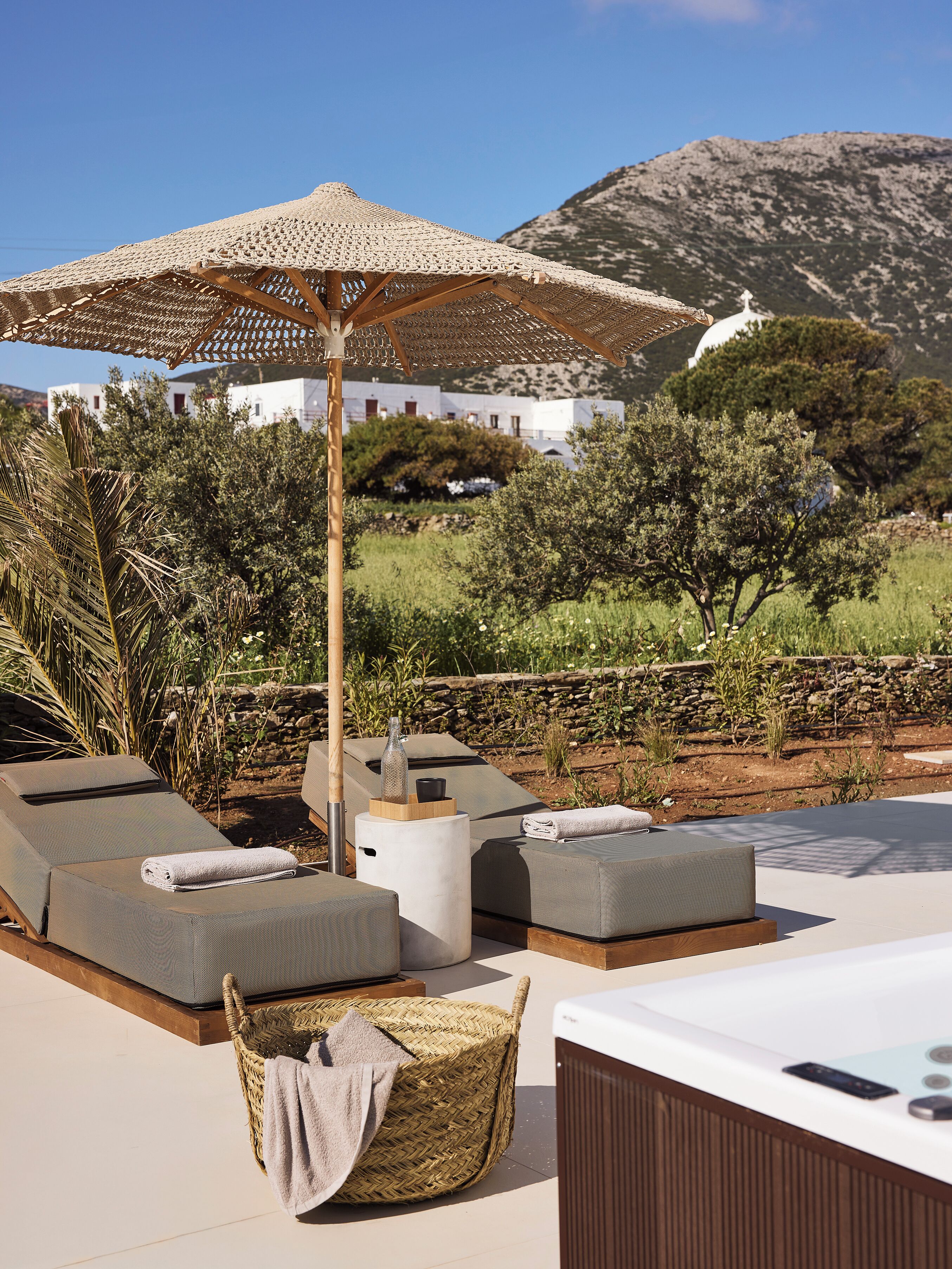 A rooftop terrace with lounge chairs, a hot tub, and a decorative umbrella.