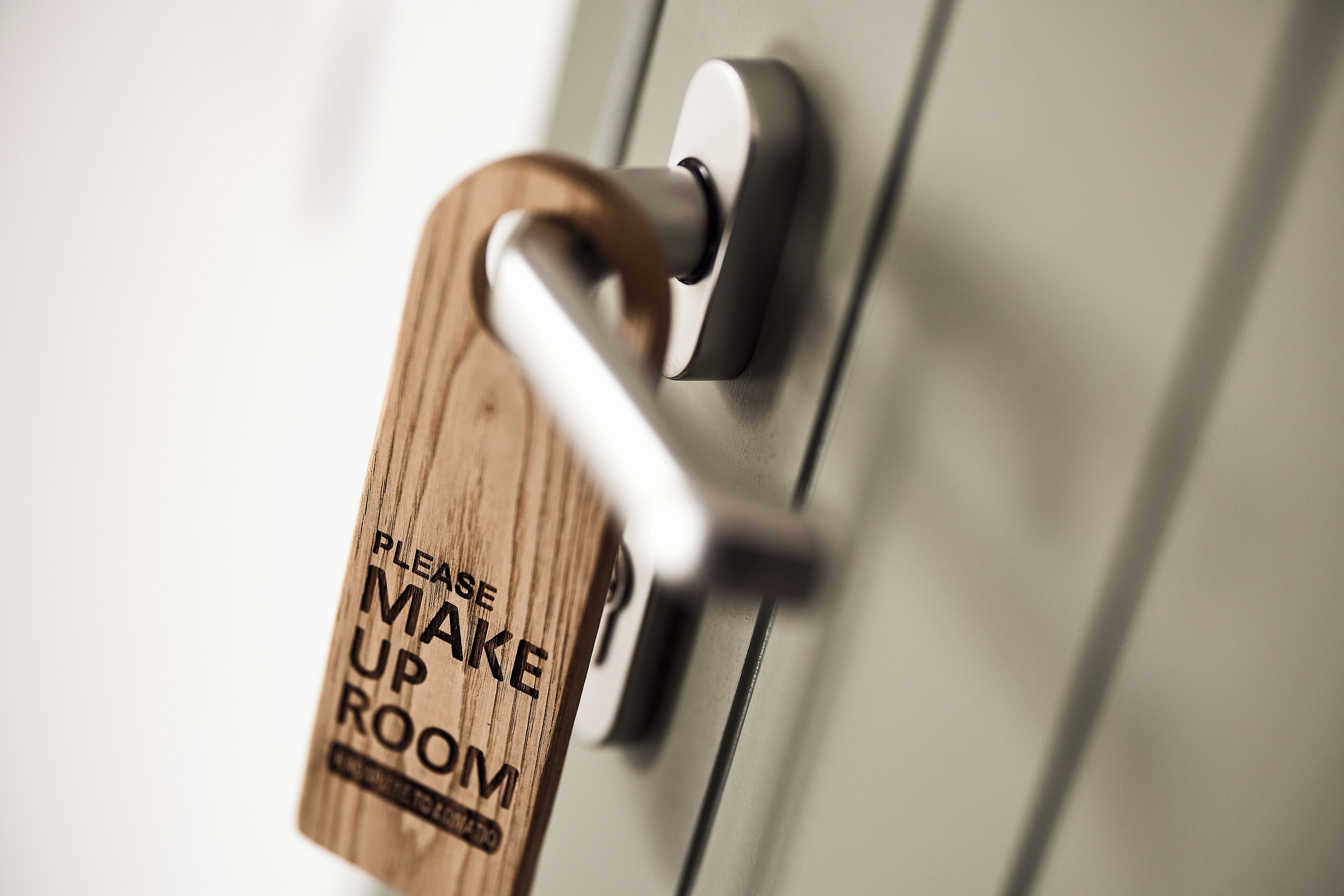 A door handle with a wooden tag that reads "PLEASE MAKE UP ROOM."