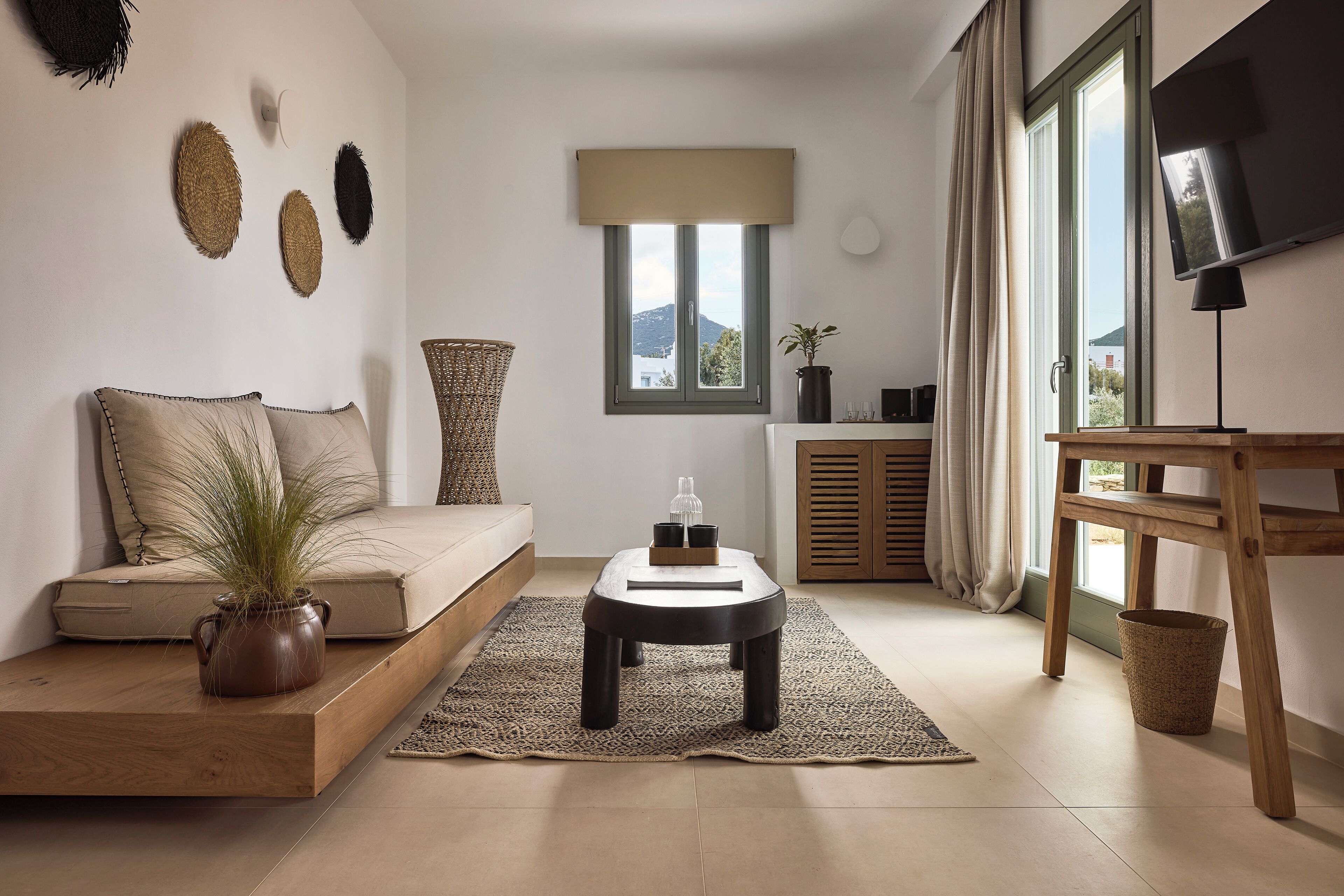 Una sala de estar moderna con sofá, una mesa de centro, televisor y ventana con vistas.
