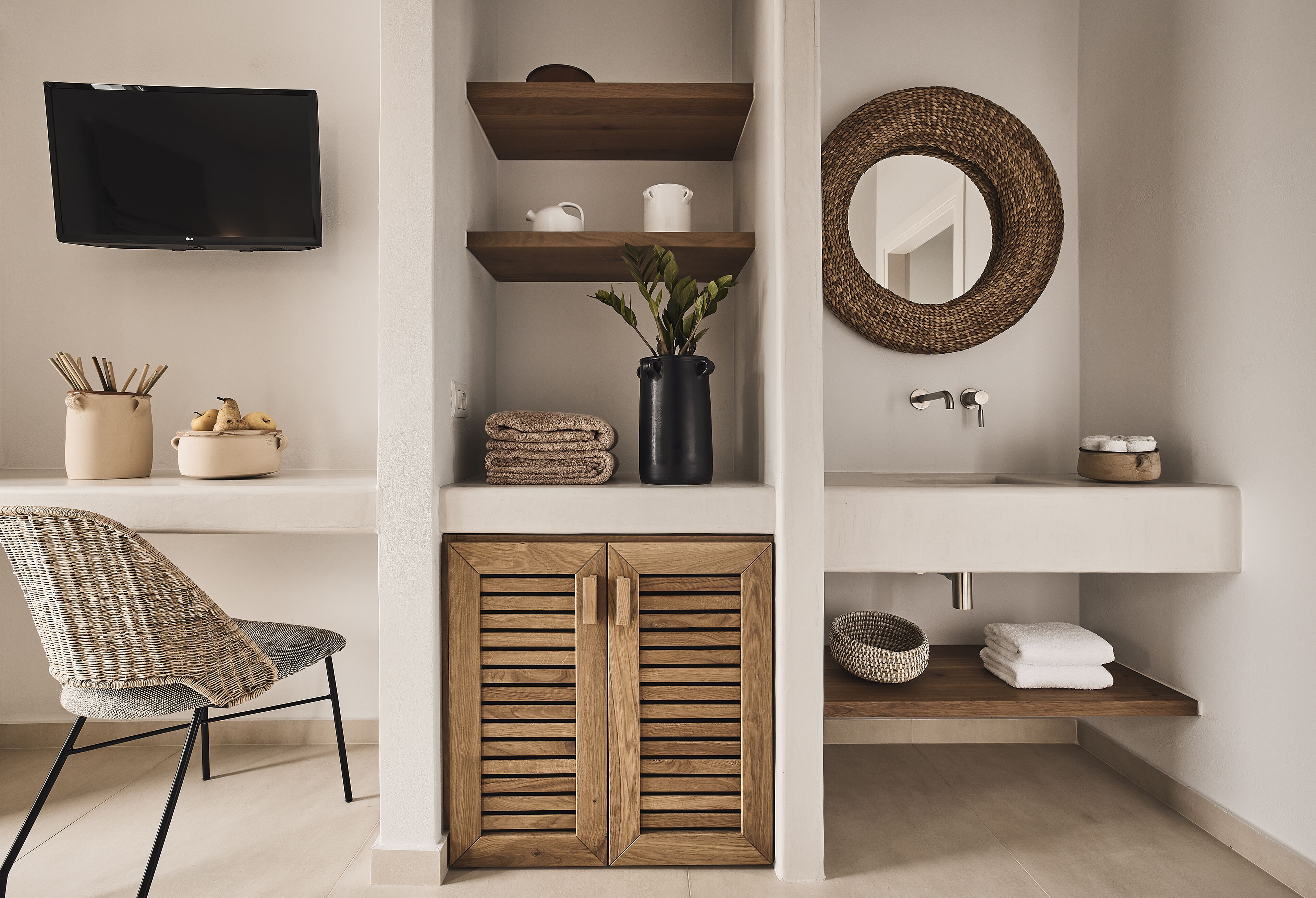 A bathroom with a wooden cabinet, a sink, a mirror, and a television mounted on the wall.