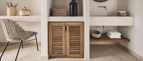 A bathroom with a wooden cabinet, a sink, a mirror, and a television mounted on the wall.
