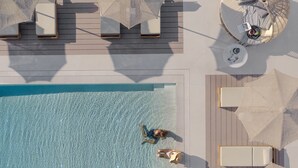 Vista aérea de un área de piscina con sillones de descanso y sombrillas.