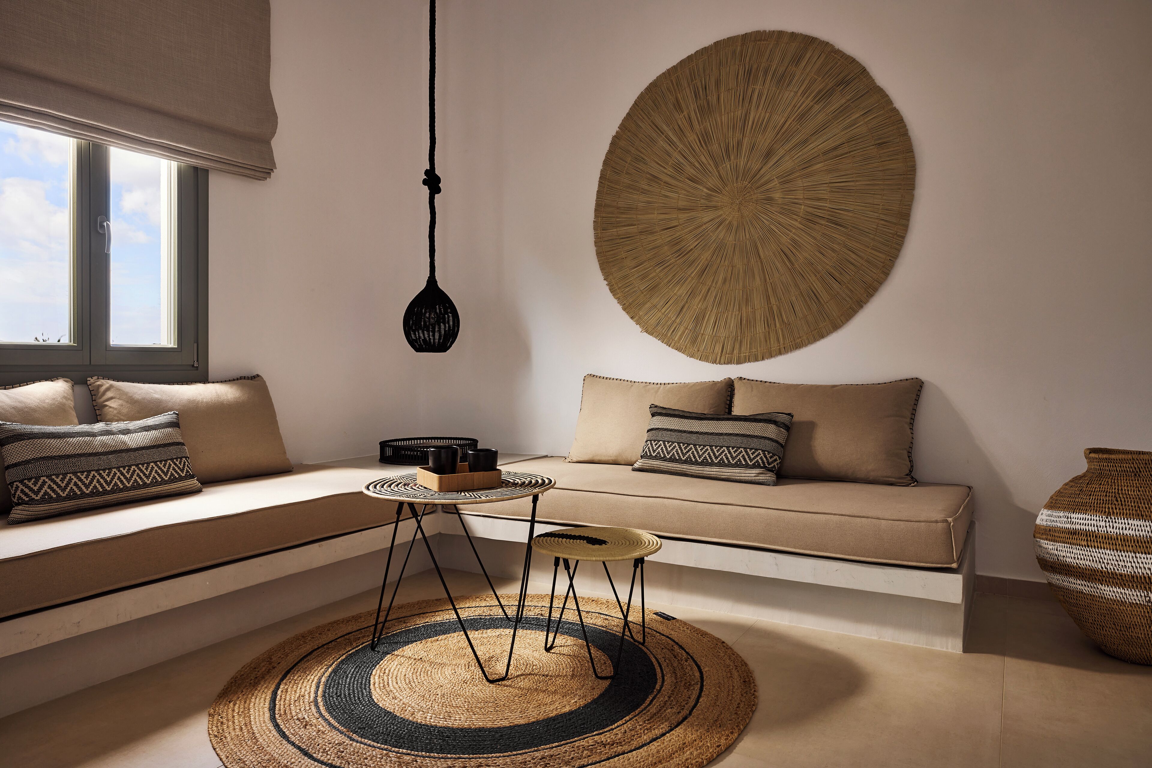 Un salon moderne avec un canapé, un tapis rond tissé et une grande décoration murale tissée.