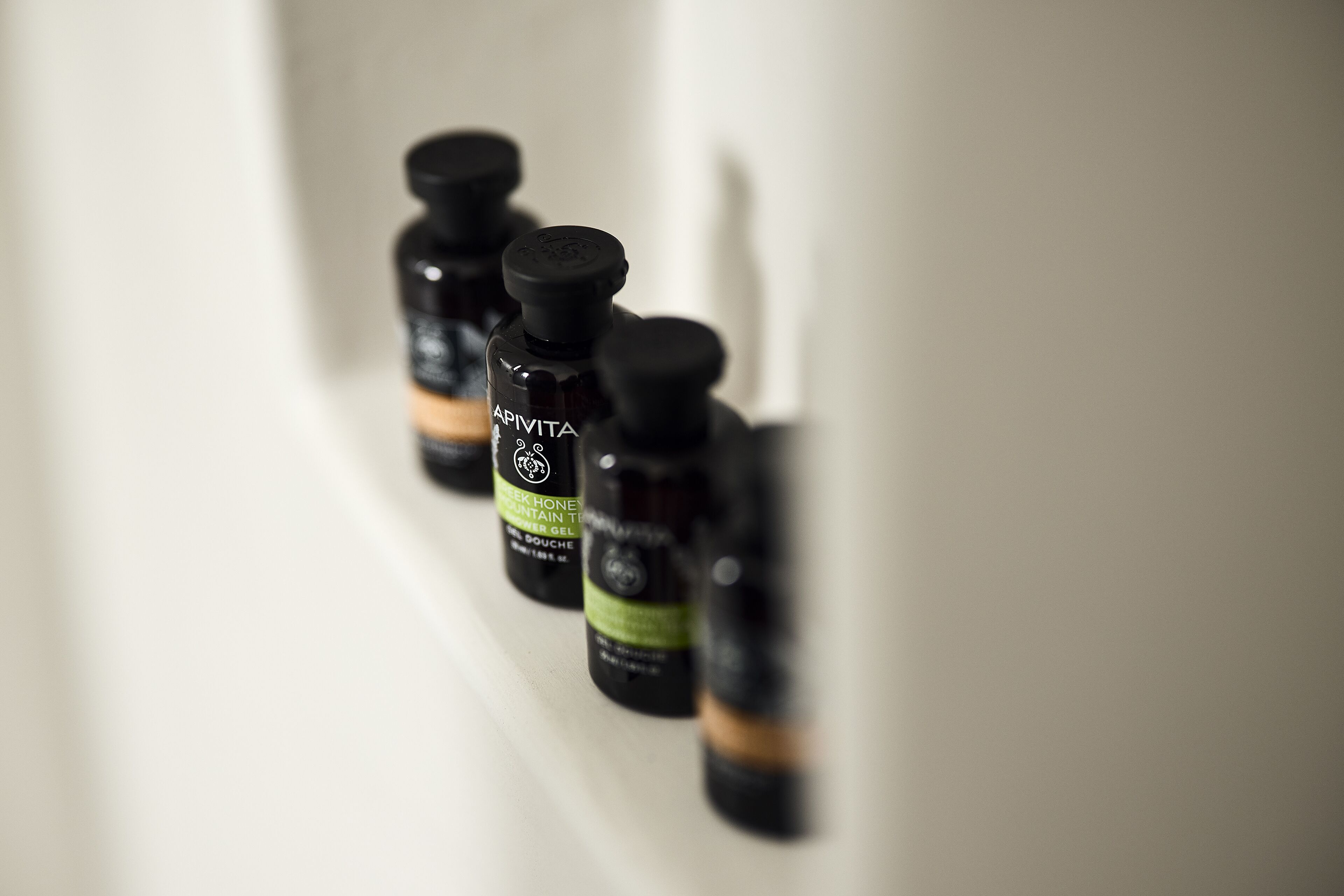 Three bottles of Apivita skincare products on a white surface.