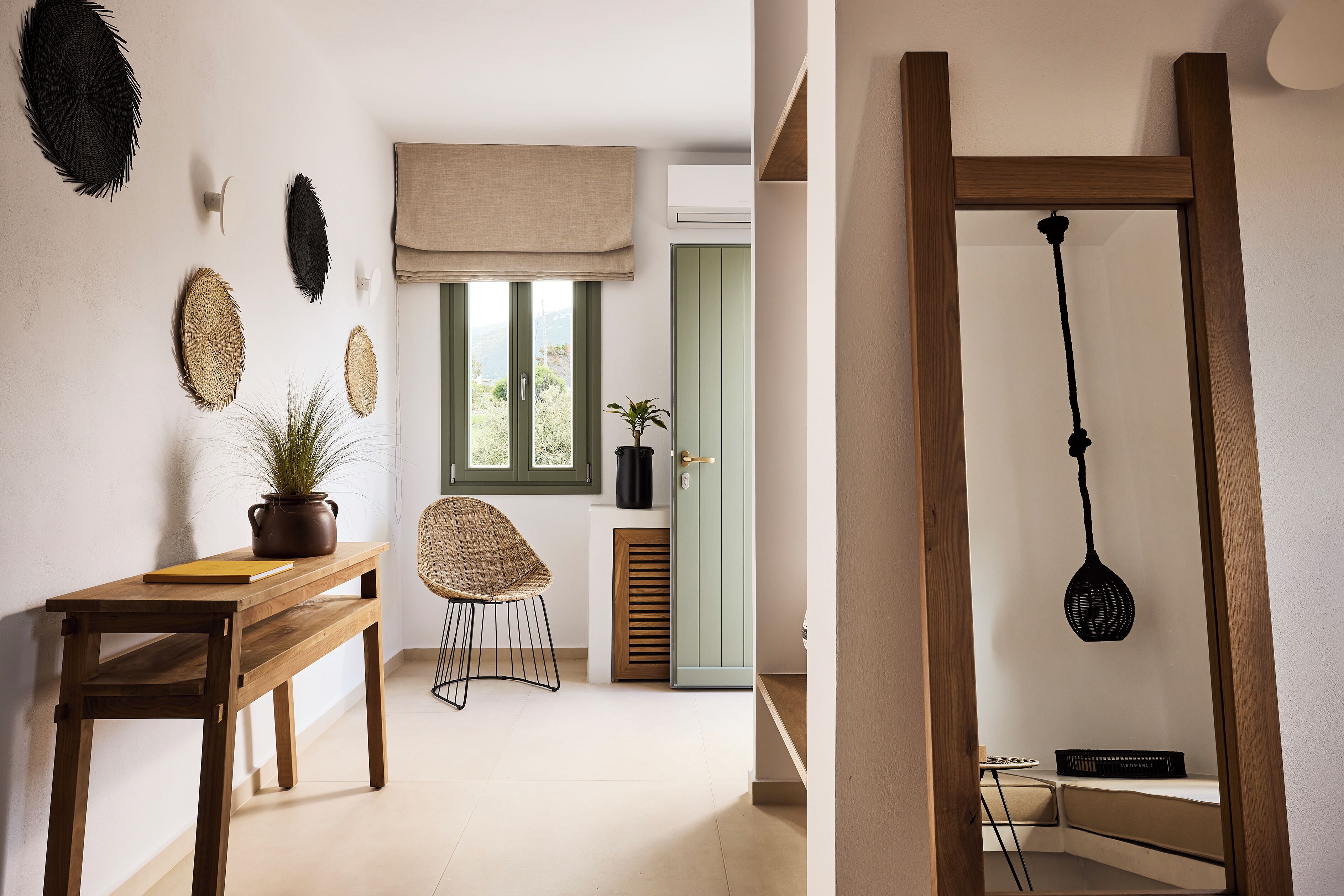A room with a wooden table, a chair, a potted plant, and a window with a view of greenery.