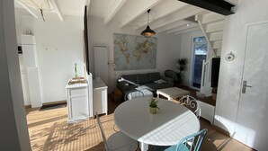Ett modernt vardagsrum med en matplats, en soffa, en karta på väggen och ett kök i bakgrunden.