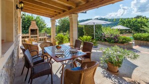 An outdoor patio with a wooden pergola, a brick oven, wicker furniture, and potted plants. - Cal Cristo, Villa with private pool in a quiet area (Pollensa)