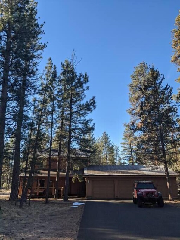 A building with a garage and a parked vehicle in front. - Home nestled in the forest just outside Sisters (Deschutes County)