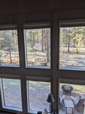 Enjoy a peaceful retreat with a forest view from the comfort of this room, featuring a seating area with a fire pit and chairs.