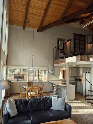 Relax in this spacious living area with a high ceiling, featuring a comfortable sofa and dining space.