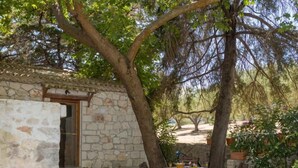 Un edificio de piedra con una puerta de madera, un muro de piedra y una mesa con sillas afuera.