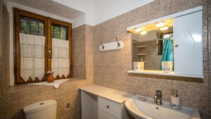 Un baño con inodoro, lavamanos y ventana con cortinas.
