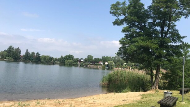 A lakeside park with a sandy beach, a wooden bench, and a picnic table. - beautiful place in the village (Elsteraue)