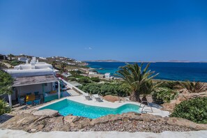 A pool area with a view of the sea, surrounded by rocks and greenery. - Caribbean dream (Mykonos)