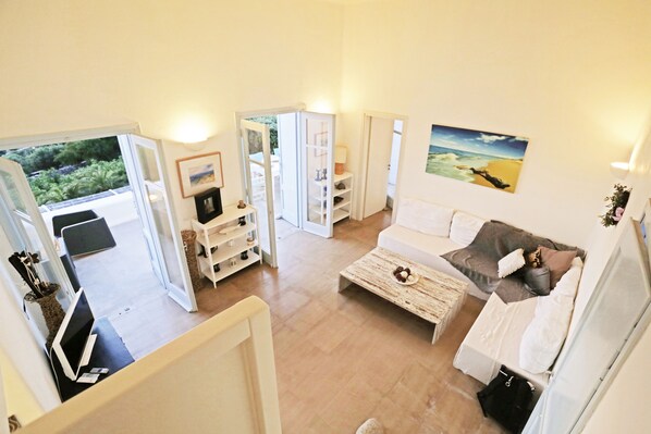 A spacious living area with a sofa, coffee table, and a painting of a beach scene.