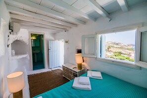 A room with a bed, a lamp, a view of the sea, a bathroom, and a window. - Caribbean dream (Mykonos)