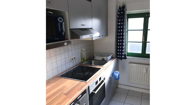 Eine Küche mit Holzarbeitsplatte, Edelstahlgeräten und einem Fenster mit Vorhängen.