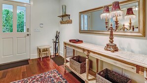 Una habitación amplia con un espejo grande, una araña y una consola de madera con cestas.