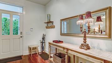Una stanza spaziosa con un grande specchio, un lampadario e un tavolino consolle in legno con cesti.