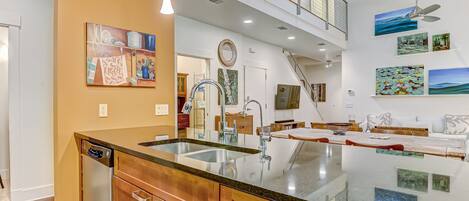 A modern kitchen with a large island, a dining area with a view, and artwork on the walls.