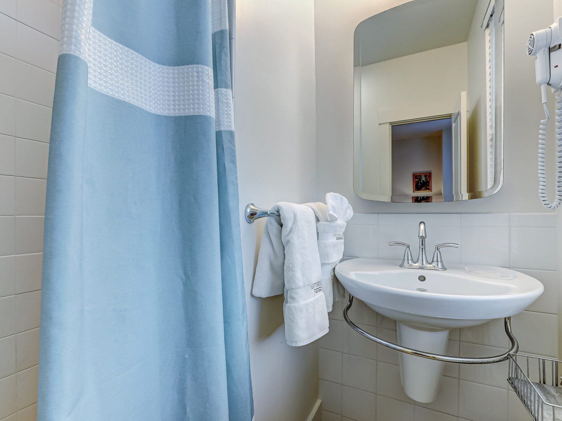A bathroom with a white sink, a mirror, and a shower curtain.