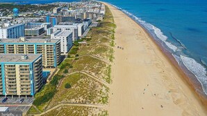 A coastal cityscape with a beach, high-rise buildings, and a clear sky. - Ocean & Bay Views, Resort Amenities, Weekly Activities & Fireworks! - Book Now (Ocean City)