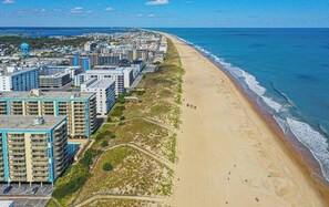 A coastal cityscape with a beach, high-rise buildings, and a clear sky.