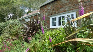 A brick house with a garden in front, including various plants and flowers. - Idyllic rural retreat - Generous ferry discounts available (Isle of Wight)