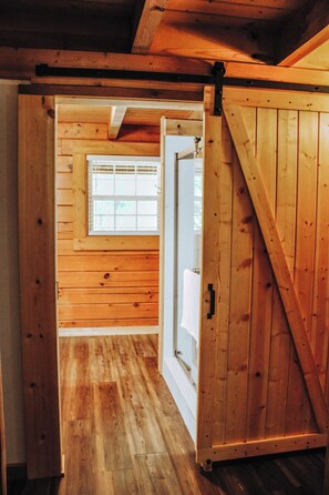 A wooden interior with a sliding door leading to a bathroom with a window.