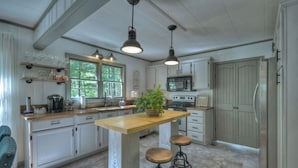 A kitchen with a central island, bar stools, a microwave, and a refrigerator.