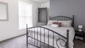 A bedroom with a bed, a nightstand, a dresser, a window, and a mirror. - Platform Holderness House (Hull)