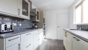 A modern kitchen with white cabinets, a grey countertop, and a stainless steel toaster. - Platform Holderness House (Hull)