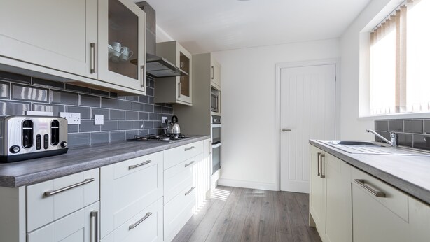 A modern kitchen with white cabinets, a grey countertop, and a stainless steel toaster.