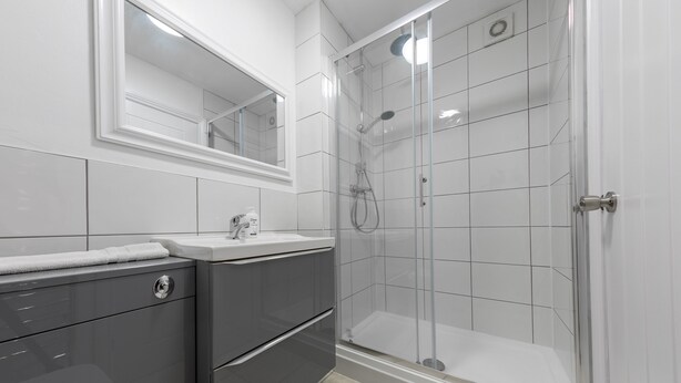 A modern bathroom with a glass-enclosed shower, a vanity with a mirror, and a toilet.