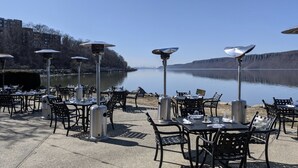 Outdoor tables and chairs arranged along a lakeside promenade with metal lamps and a clear view of the water. - LUXE 3BD/2BA 29 min>NYC w/Parking & deck  (Hastings-on-Hudson)
