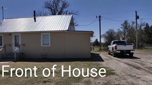 A single-story house with a metal roof, a front door, and a small porch.