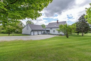 Ein zweigeschossiges Haus mit Auffahrt, Rasen und Bäumen.