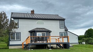 Une maison à deux étages dotée d’un patio couvert et d’une grande pelouse à l’avant.