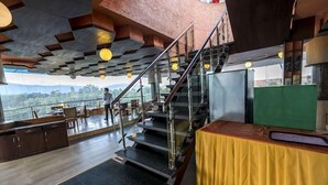 A modern interior with a staircase, dining area, and a view of the outdoors. - Summit Residency Airport Hotel (Kathmandu)